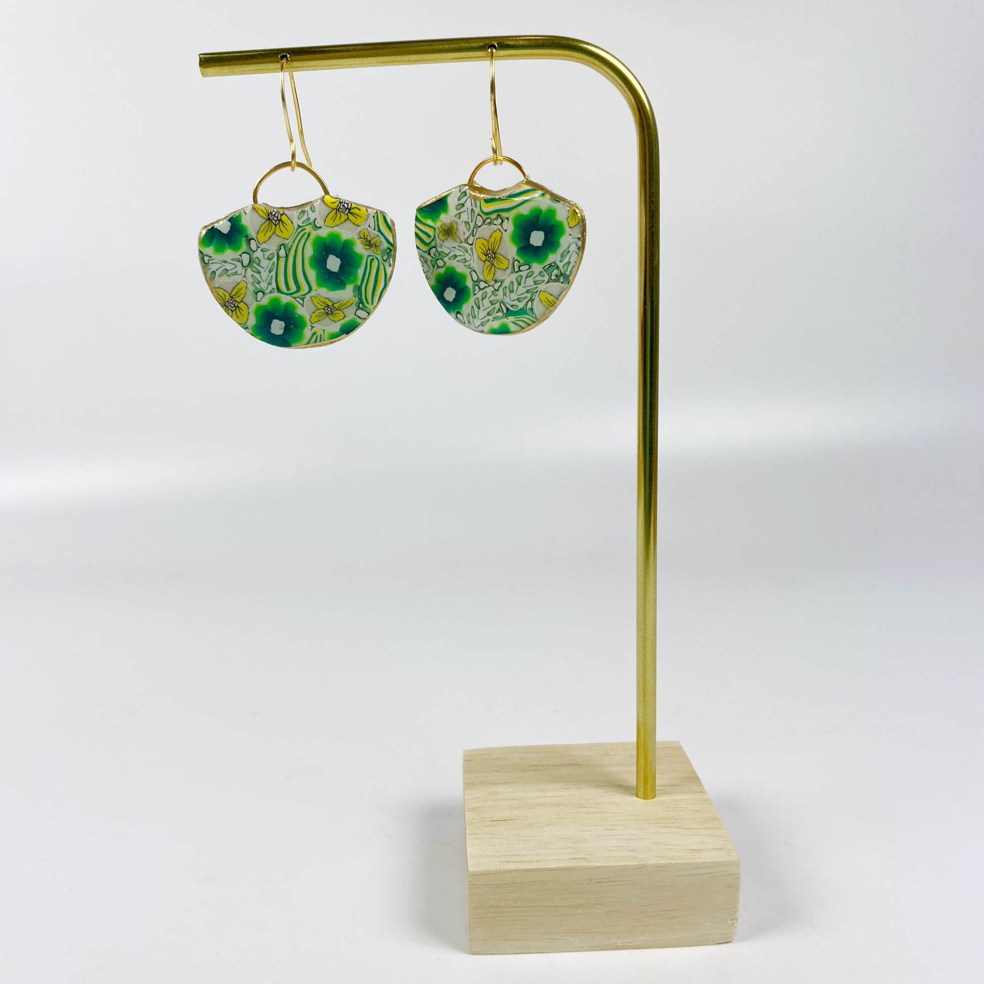 Green Flower Handmade Polymer Clay Earrings on a brass earrings display stand