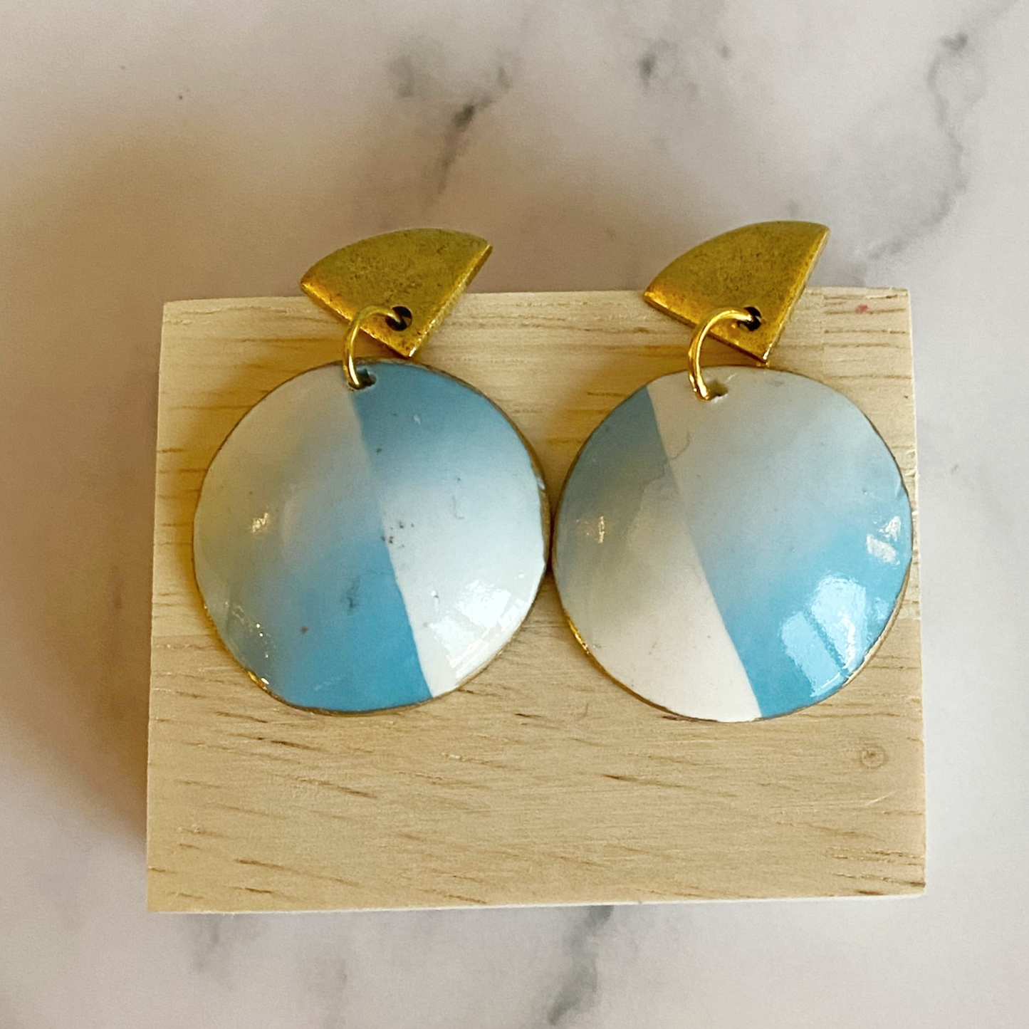 Blue Cloud Handmade Polymer Clay Dangle Earrings resting on a wooden block